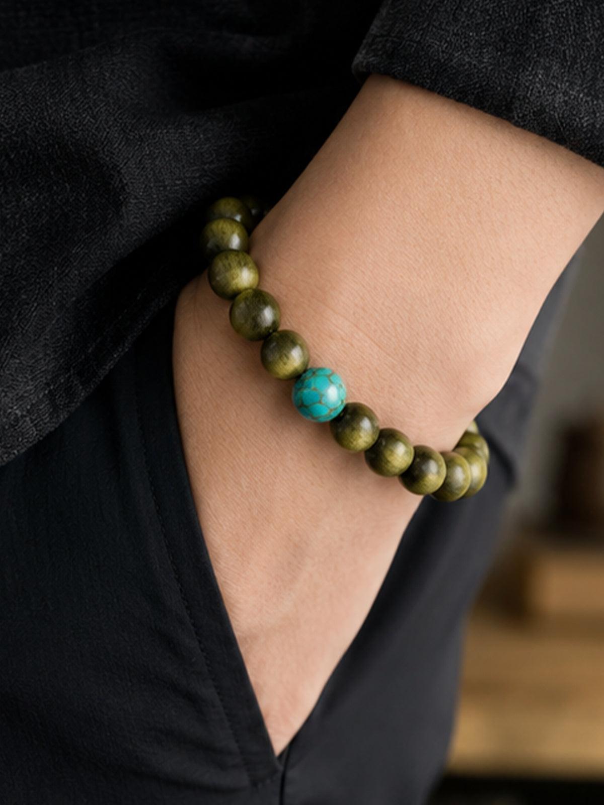Unisex Green Sandalwood Turquoise Bracelet worn on wrist with plain neutral background. Its timeless design ensures it stays a staple in your jewelry collection for years.